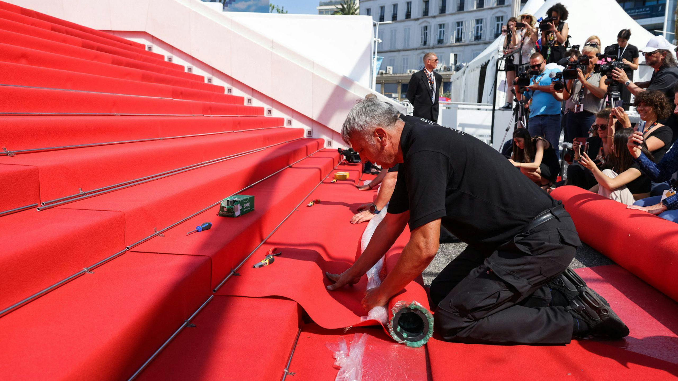 Un operario del Festival de Cannes coloca la alfombra roja de la escalinata en la edición 75 de la muestra